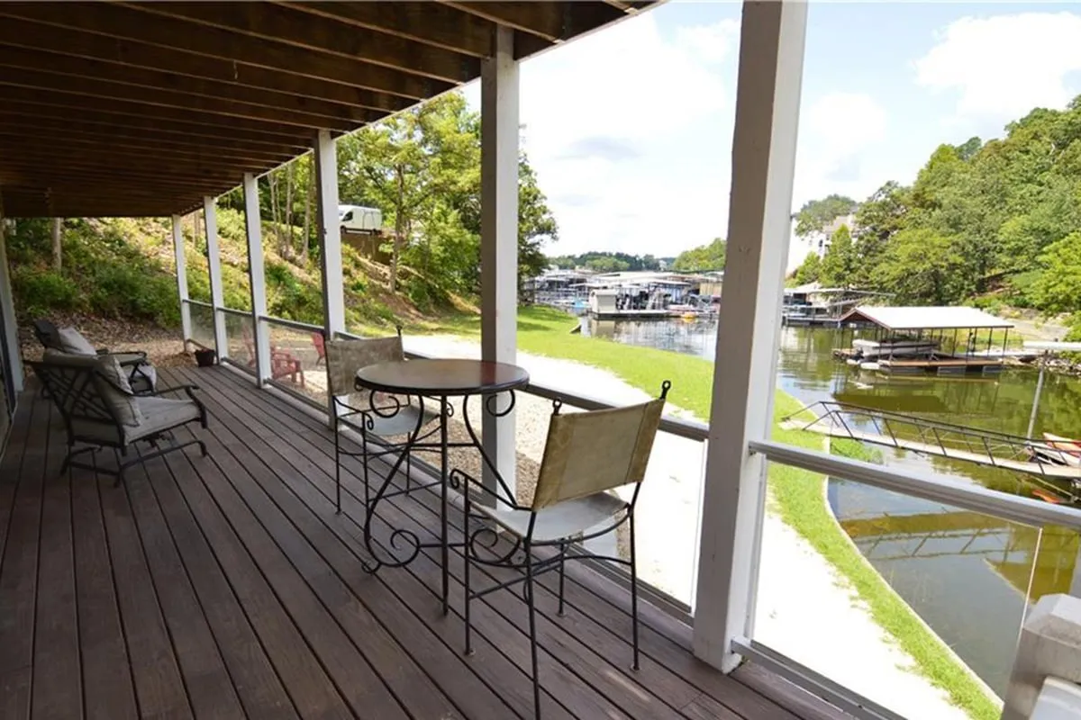 This image features an inviting outdoor seating area overlooking the water, surrounded by greenery. The view is serene and open, with space for multiple people to relax together, enjoy a drink, or converse while taking in the scenery.