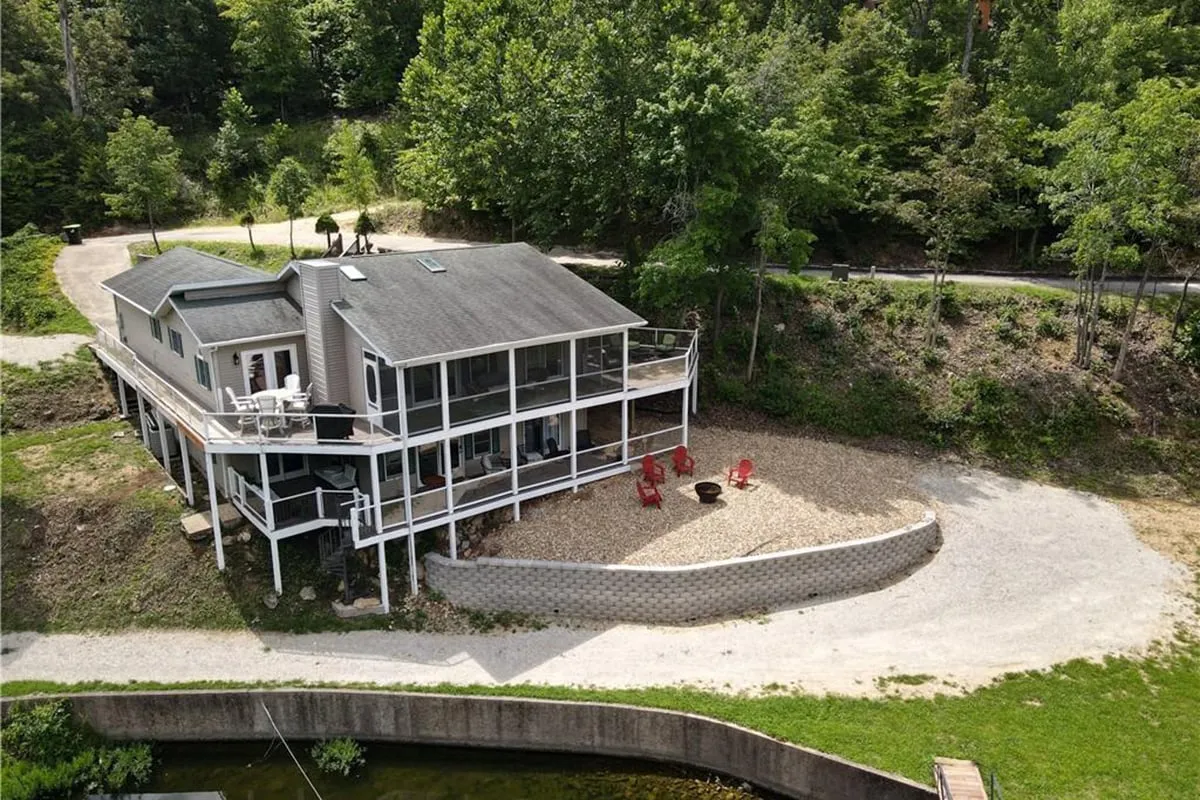 This exterior image features the house with its inviting patio, red chairs arranged around a fire pit, and lush surrounding greenery. The scene suggests ample space for outdoor relaxation and family gatherings, with a tranquil, nature-filled atmosphere perfect for pets to explore on-leash.